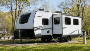 RV connected to a fresh-water hose at a spring campsite while being de-winterized.